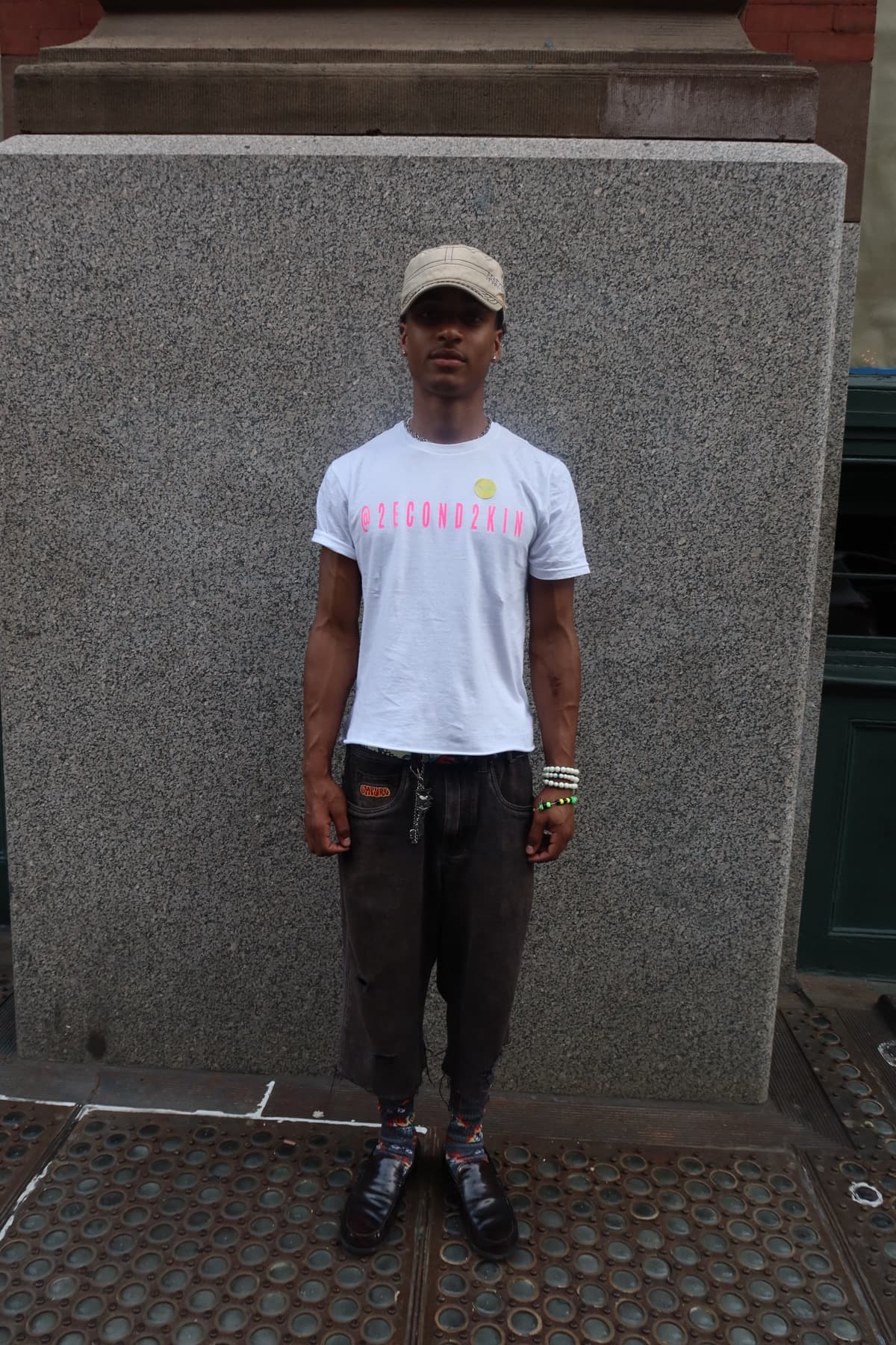 FaurY standing against a plain doorway in a 2econd2kin Magazine tee