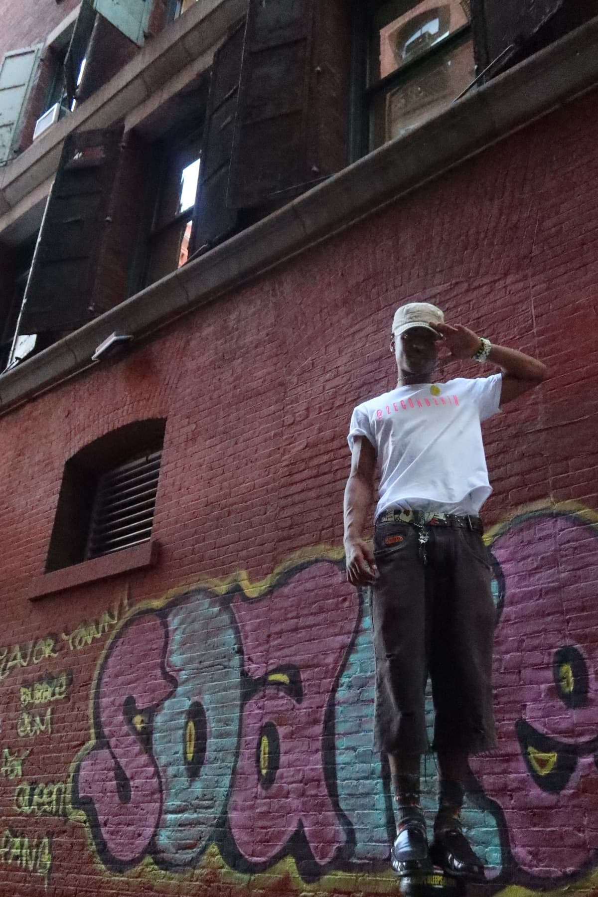 FaurY standing against a graffiti-covered brick wall