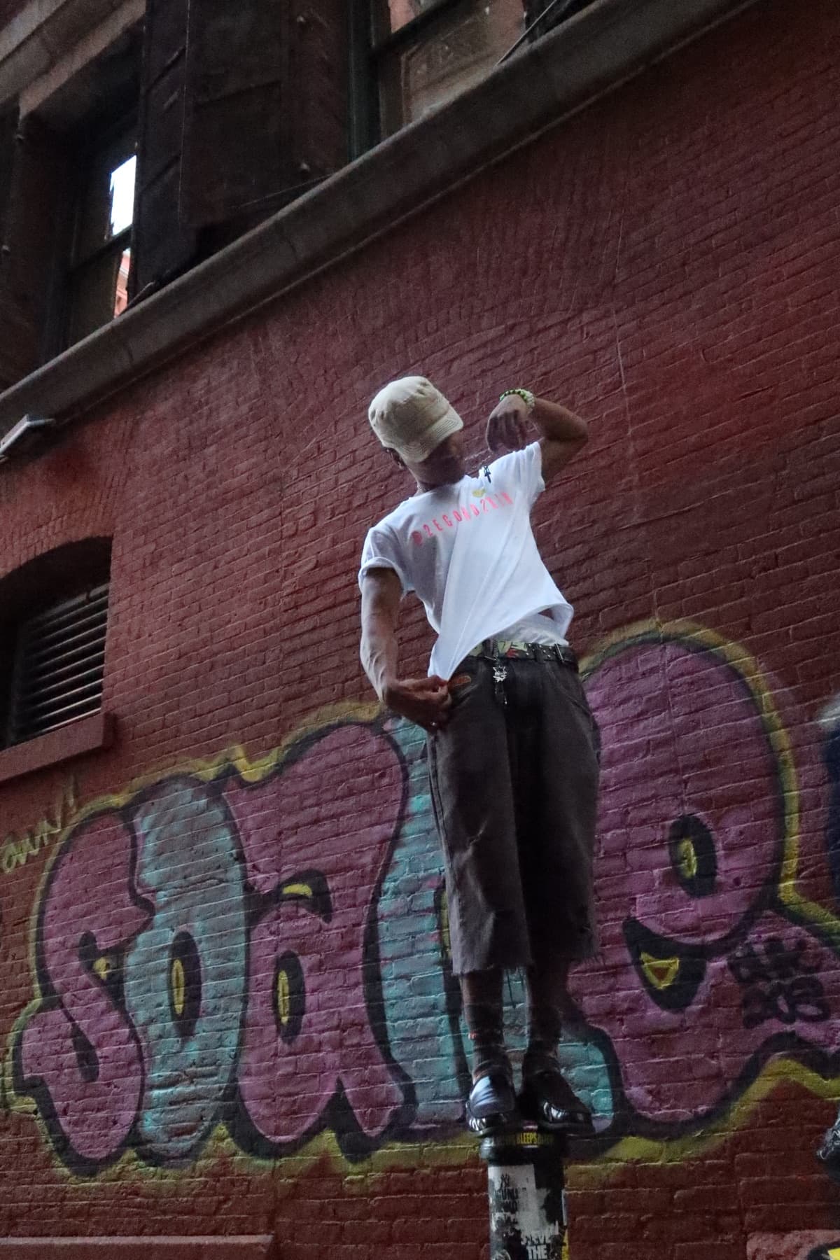 FaurY climbing a fire escape ladder against a graffiti wall