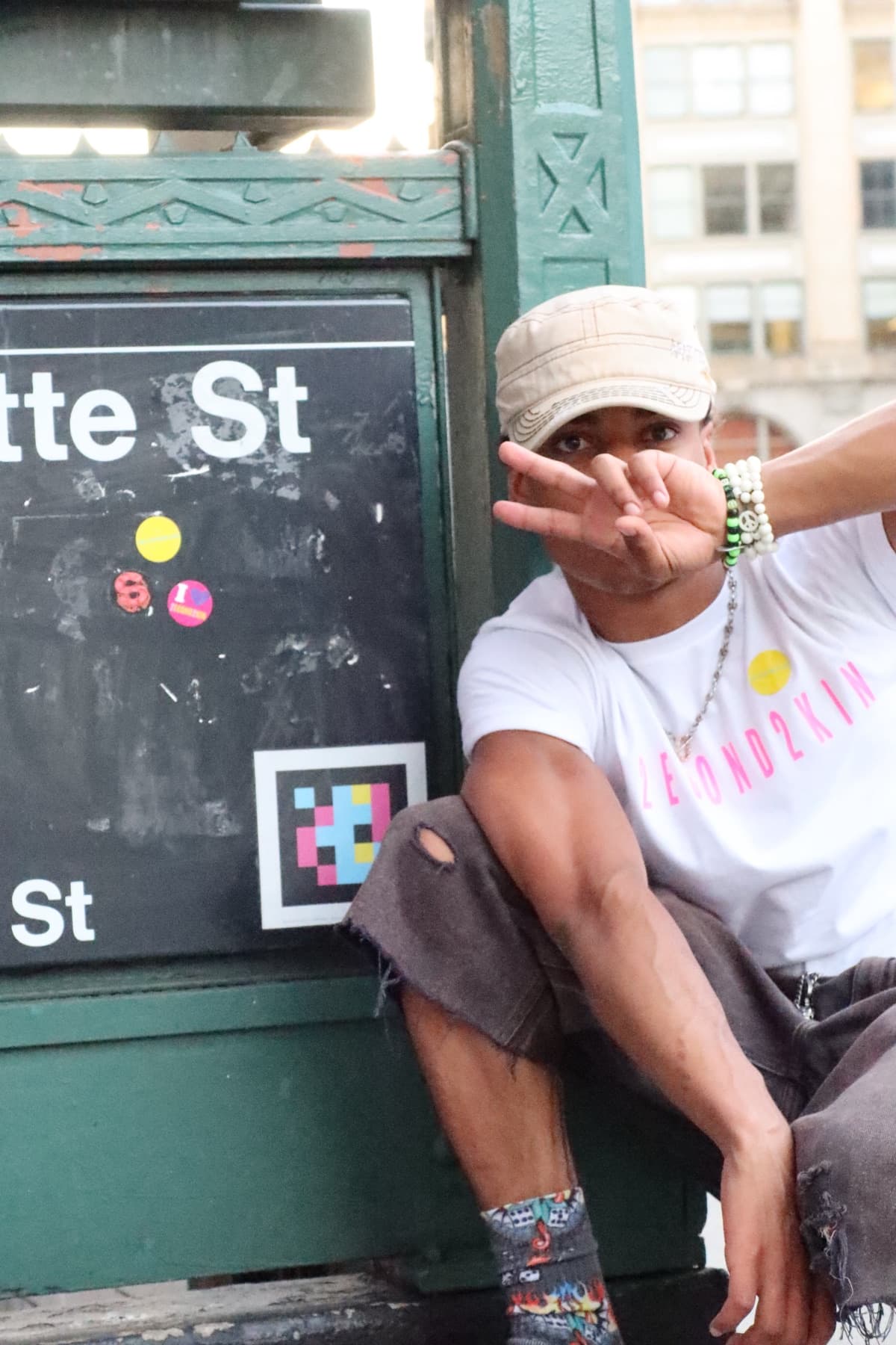 FaurY throwing a peace sign beside a subway station sign