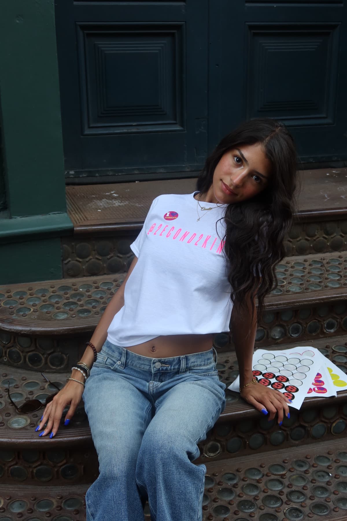 Model seated on brownstone steps, hand resting on head
