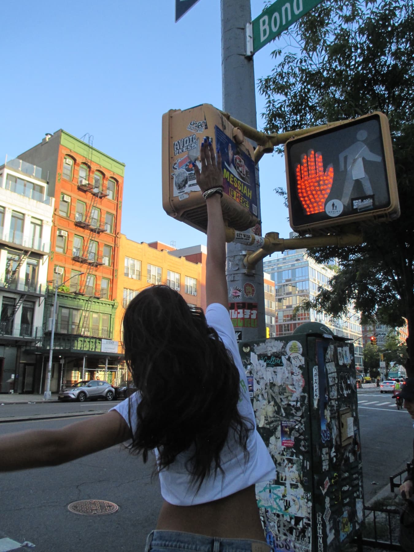 Model reaching up to a street sign, back to camera